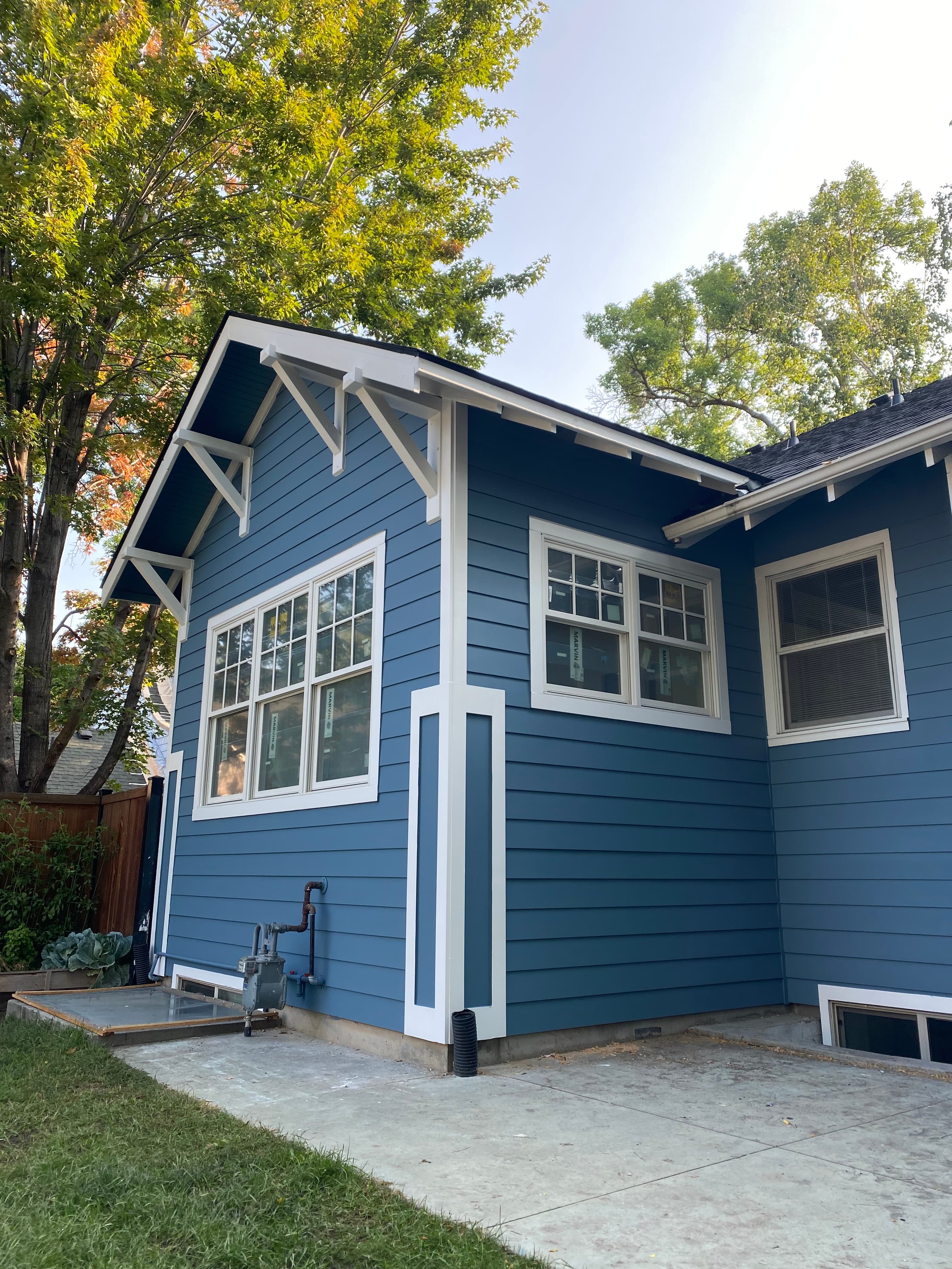 Blue lap-sided residence with white window trim and bracketed eaves