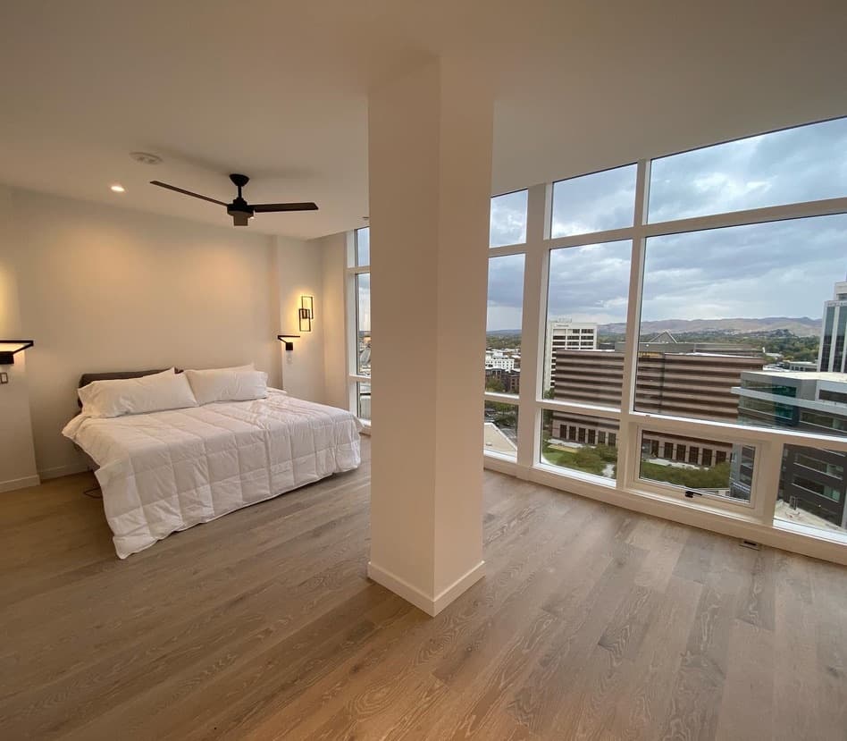 Bedroom with floor-to-ceiling windows and a view over a downtown skyline
