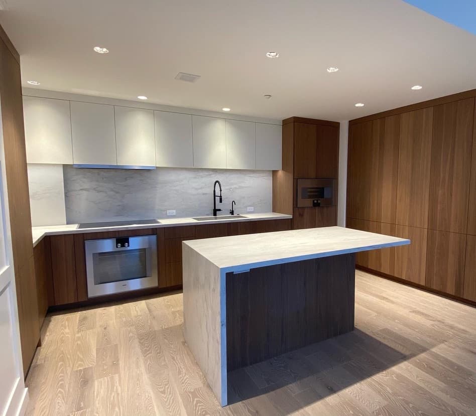 Kitchen with walnut and white cabinets and a stone waterfall island