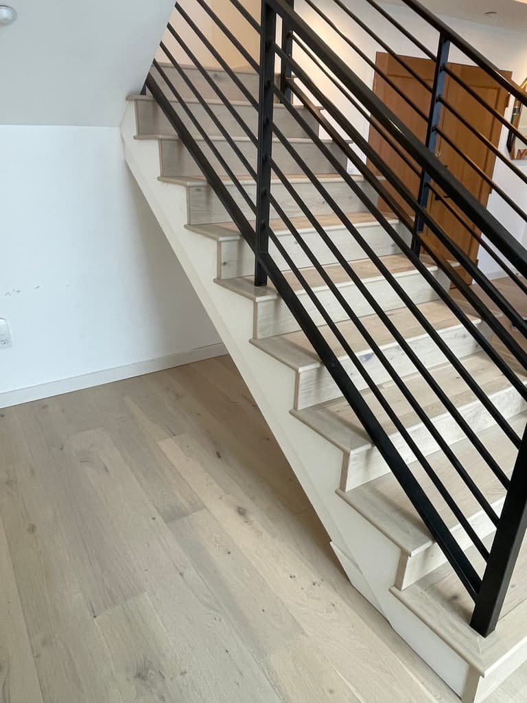 Stair with light wood treads and a black metal rail
