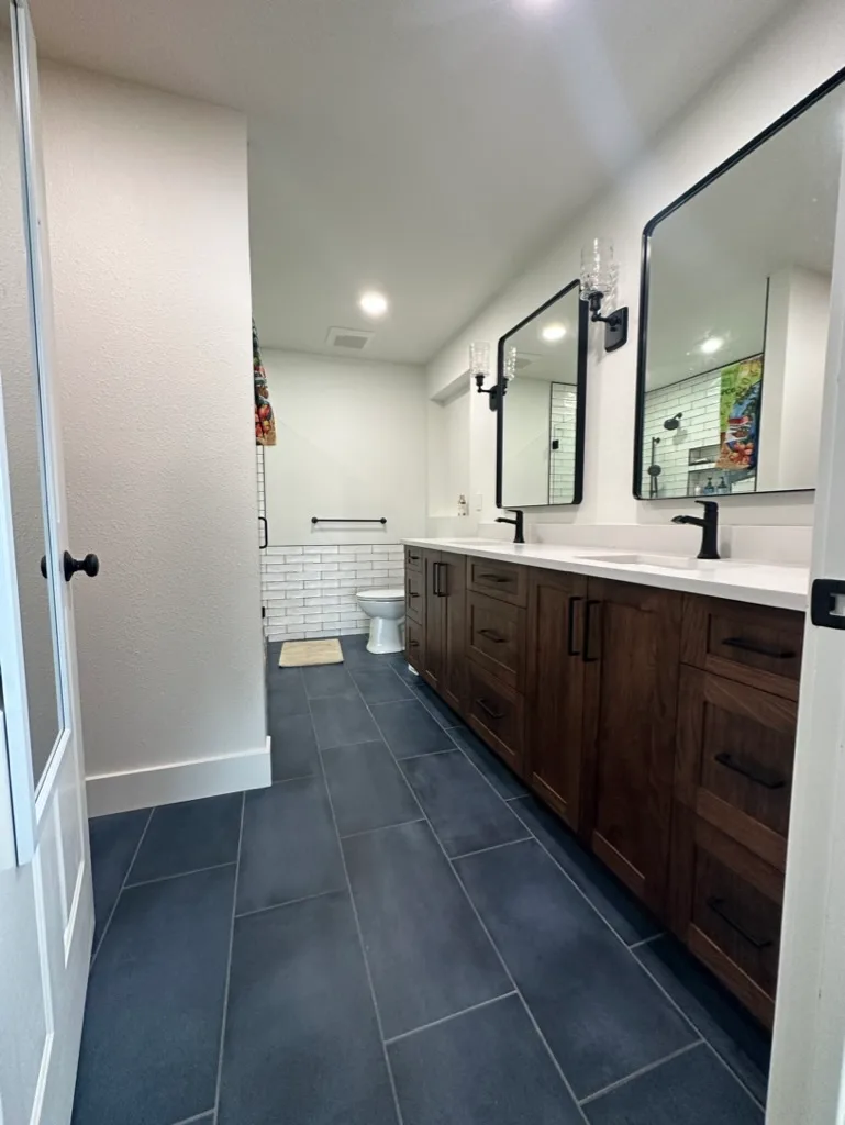 Double vanity with dark wood cabinets and tile wainscot