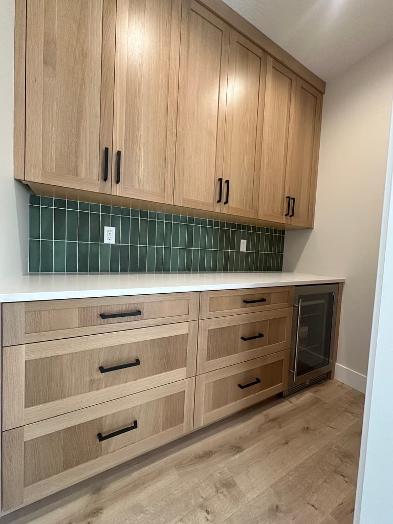 Butler's pantry with light wood cabinets, a green tile backsplash, and a beverage fridge