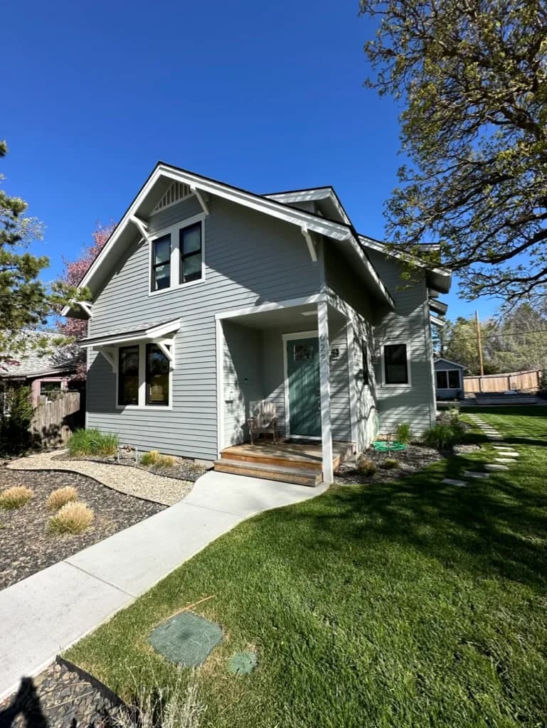 Sage craftsman residence with bracketed eaves, a covered porch, and a green front door
