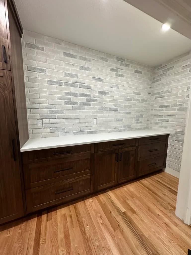 Pantry with wood cabinetry and a brick backsplash