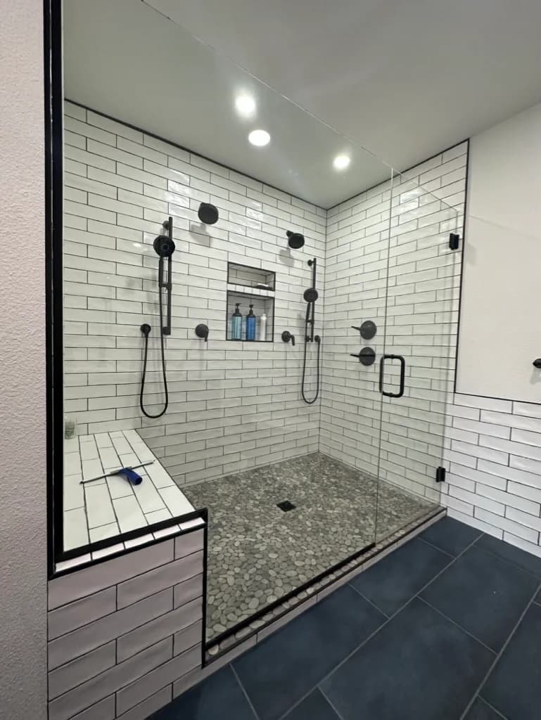 Walk-in shower with subway tile, a bench, and dark fixtures