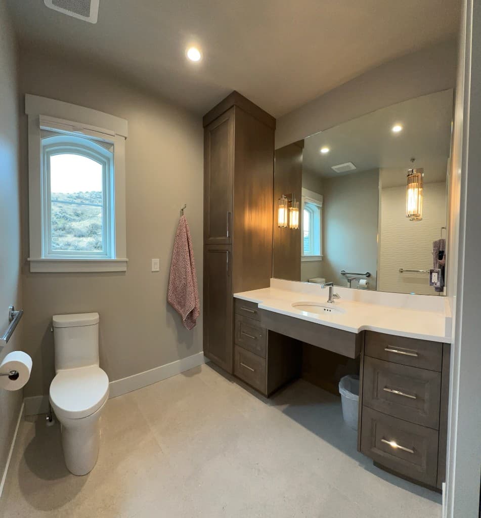 Bathroom with a wood vanity, an arched window, and a hillside view