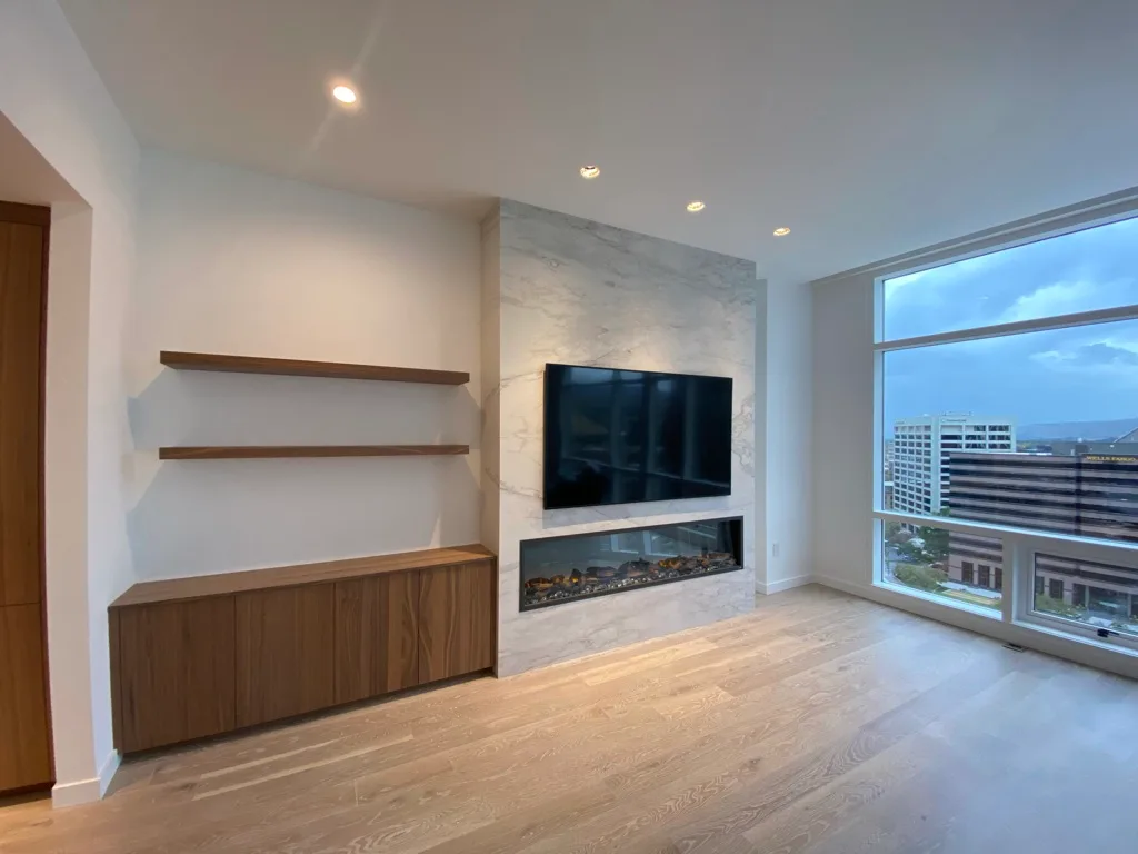 Living room with a marble fireplace wall and built-in cabinetry, from Rainier Construction project photography