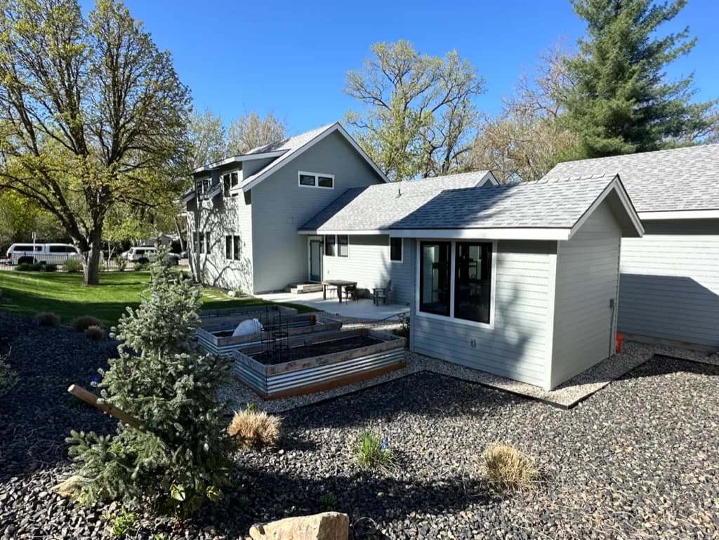 Rear of a residence with a single-story wing, a patio, and raised garden beds