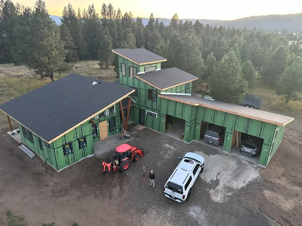 Aerial view of the same residence with multiple roof planes among pine trees
