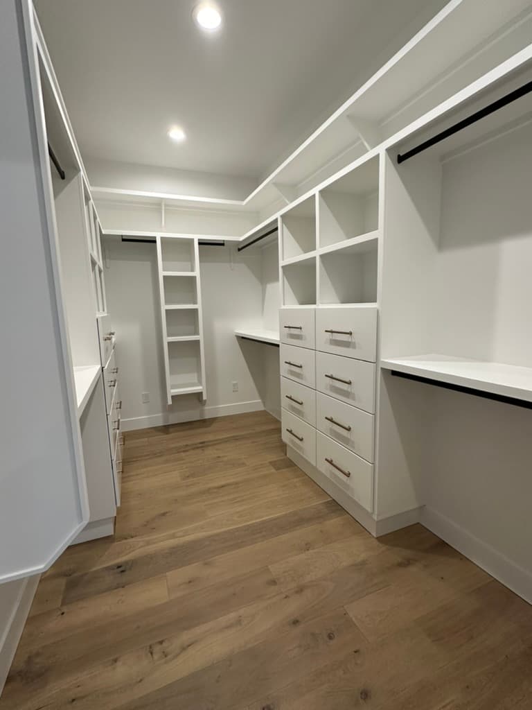 Walk-in closet with white built-in shelving and drawers