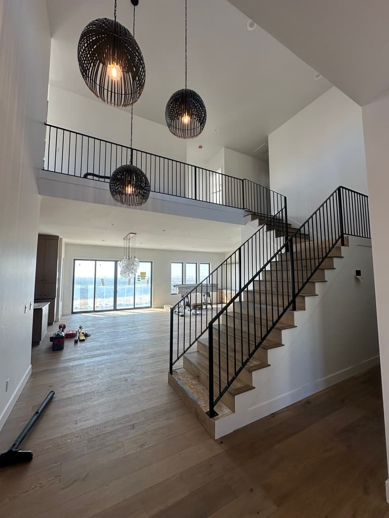 The same great room during finishing, with the stair, loft rail, and pendants in place