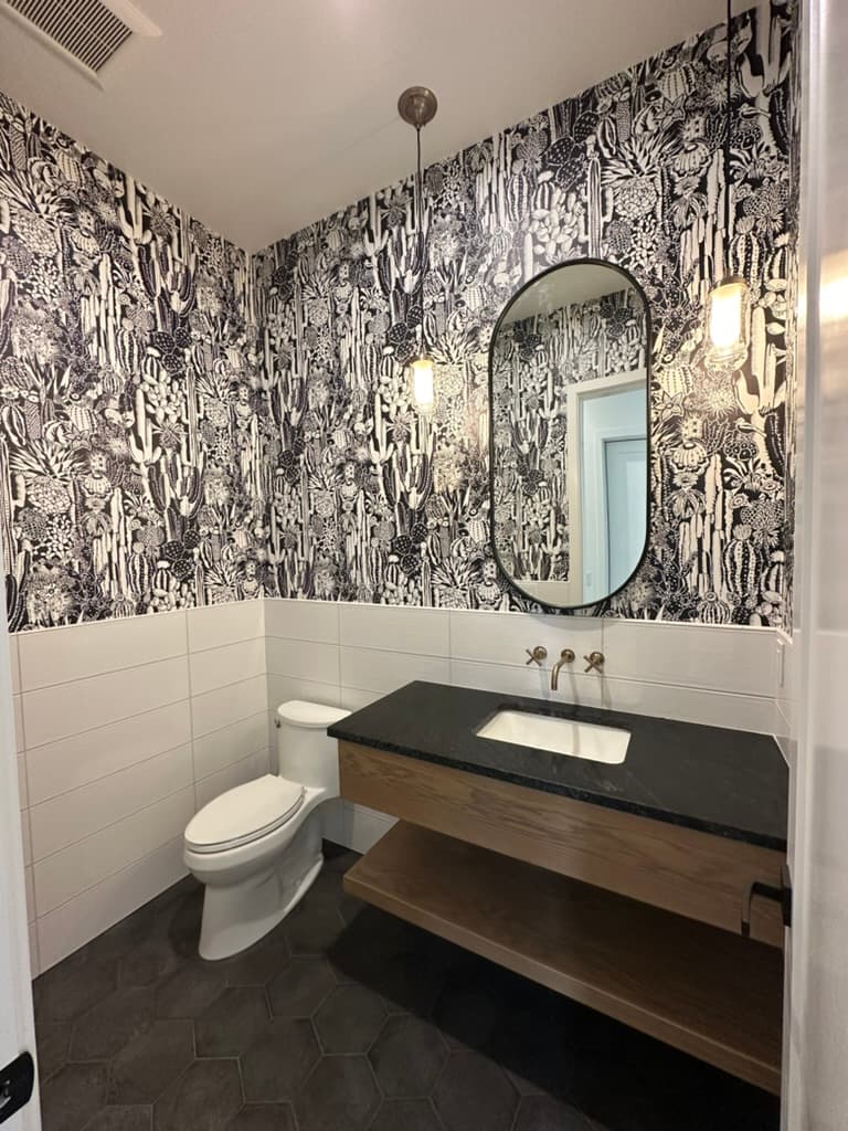 Powder room with a patterned wallpaper, an oval mirror, and a floating wood vanity