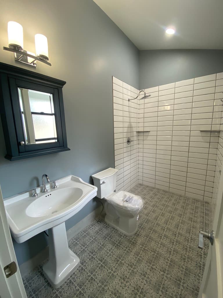 Bathroom with a pedestal sink, a dark medicine cabinet, and a tiled shower
